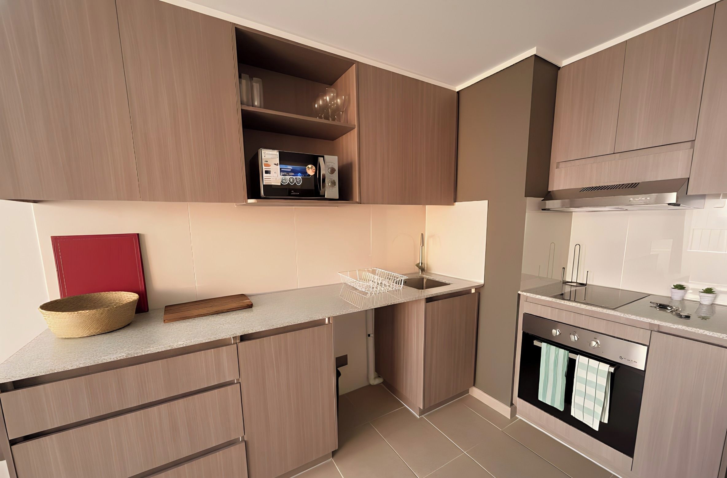 A modern kitchen with wooden cabinets, a built-in microwave, and a stainless steel oven.