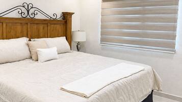 Ein Schlafzimmer mit einem Bett, einem Deckenventilator, einer Nachttischlampe und einem Fenster mit Jalousien.