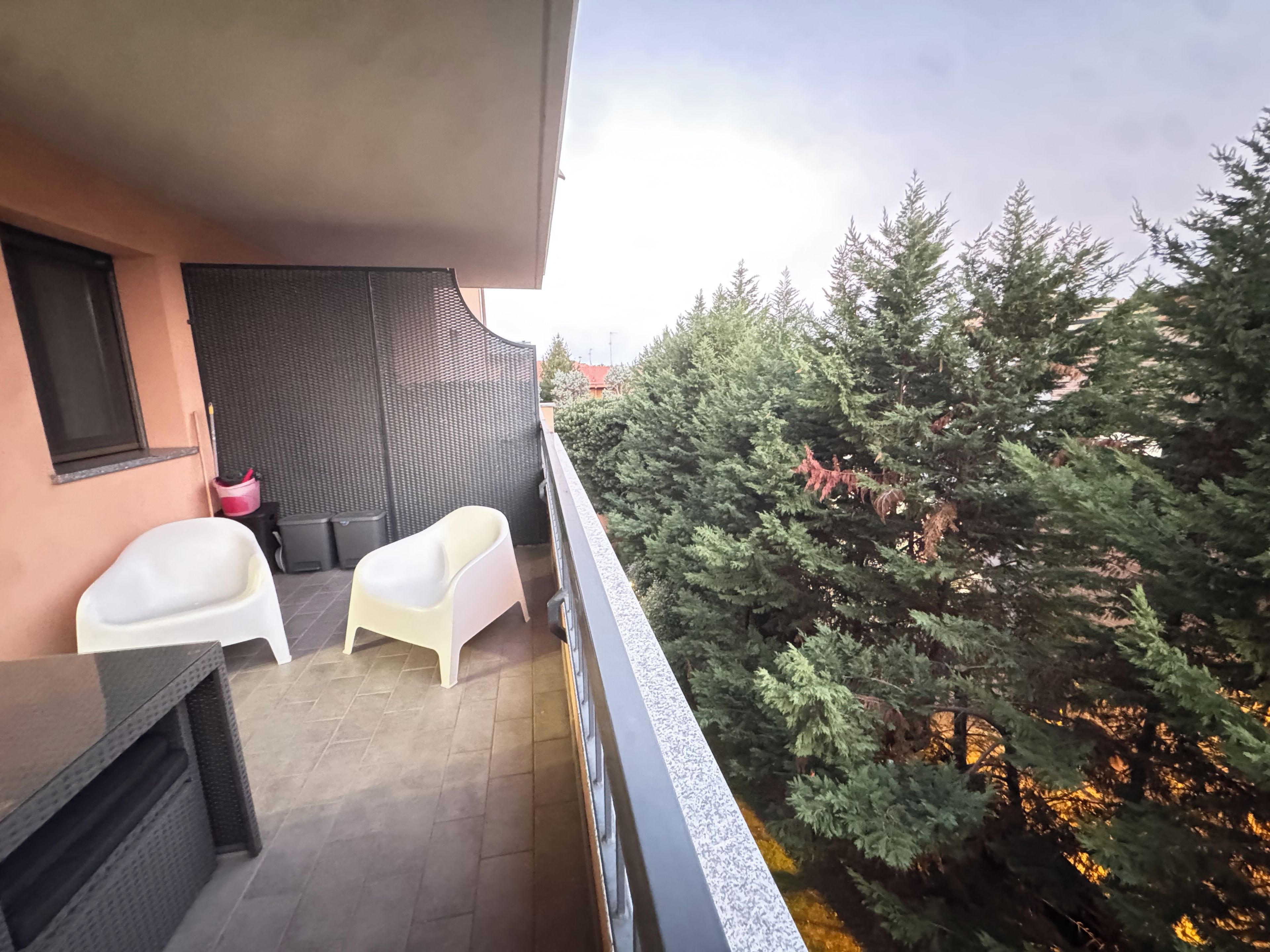 Un balcon avec un coin salon, une petite table et un pot de fleurs.