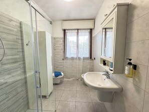 A bathroom with a glass-enclosed shower, a toilet, a sink, and a mirror.