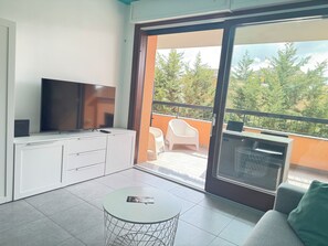 A balcony with a TV, a sofa, and a dining area with chairs.