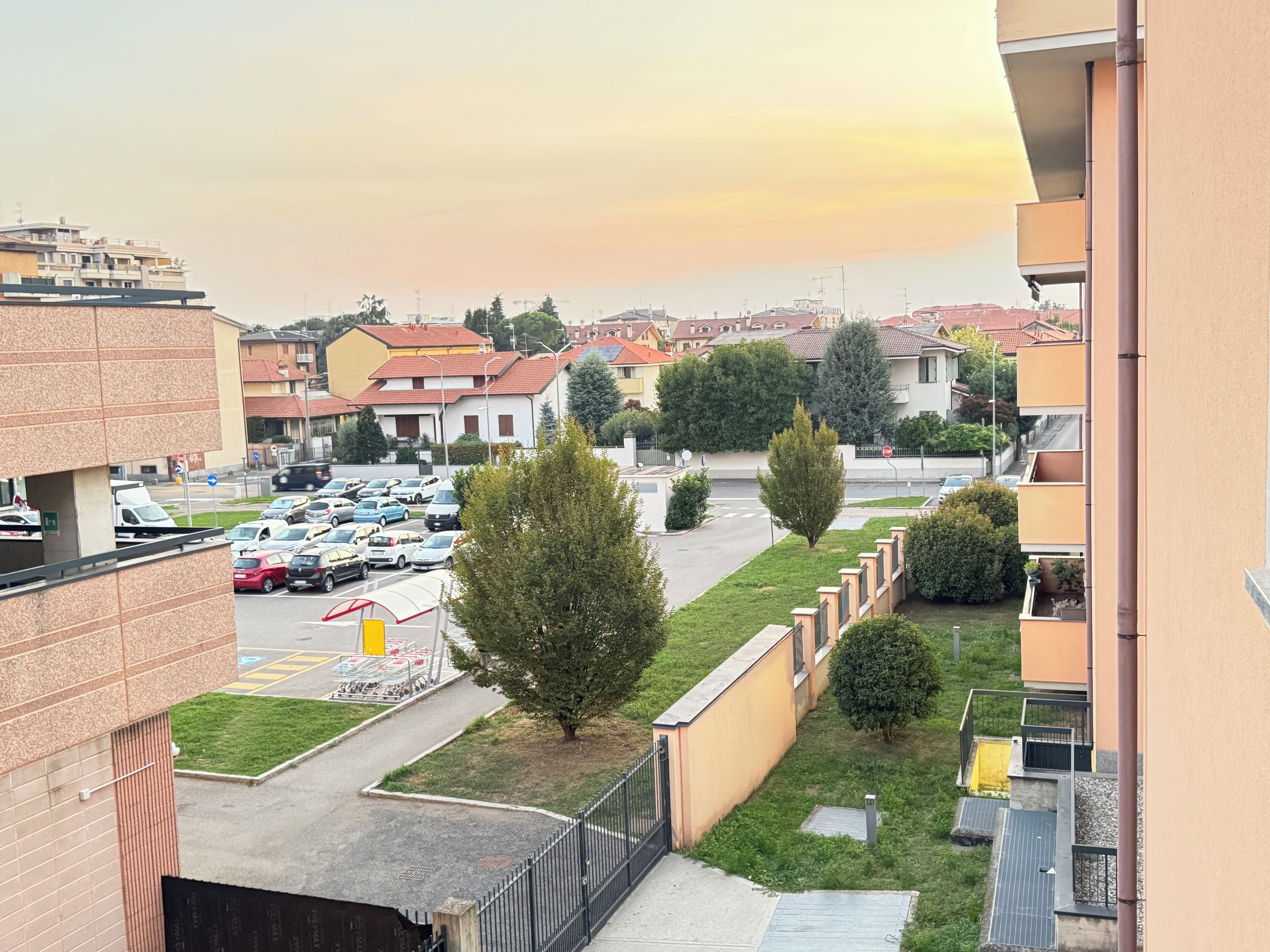 Un quartier résidentiel avec un parking, des immeubles à plusieurs étages et un ciel dégagé.