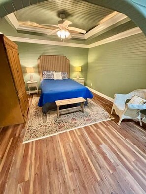 A bedroom with a bed, nightstands, a bench, a chair, and a ceiling fan. - Yellow Buoy at Pickwick Lake (Hardin County)