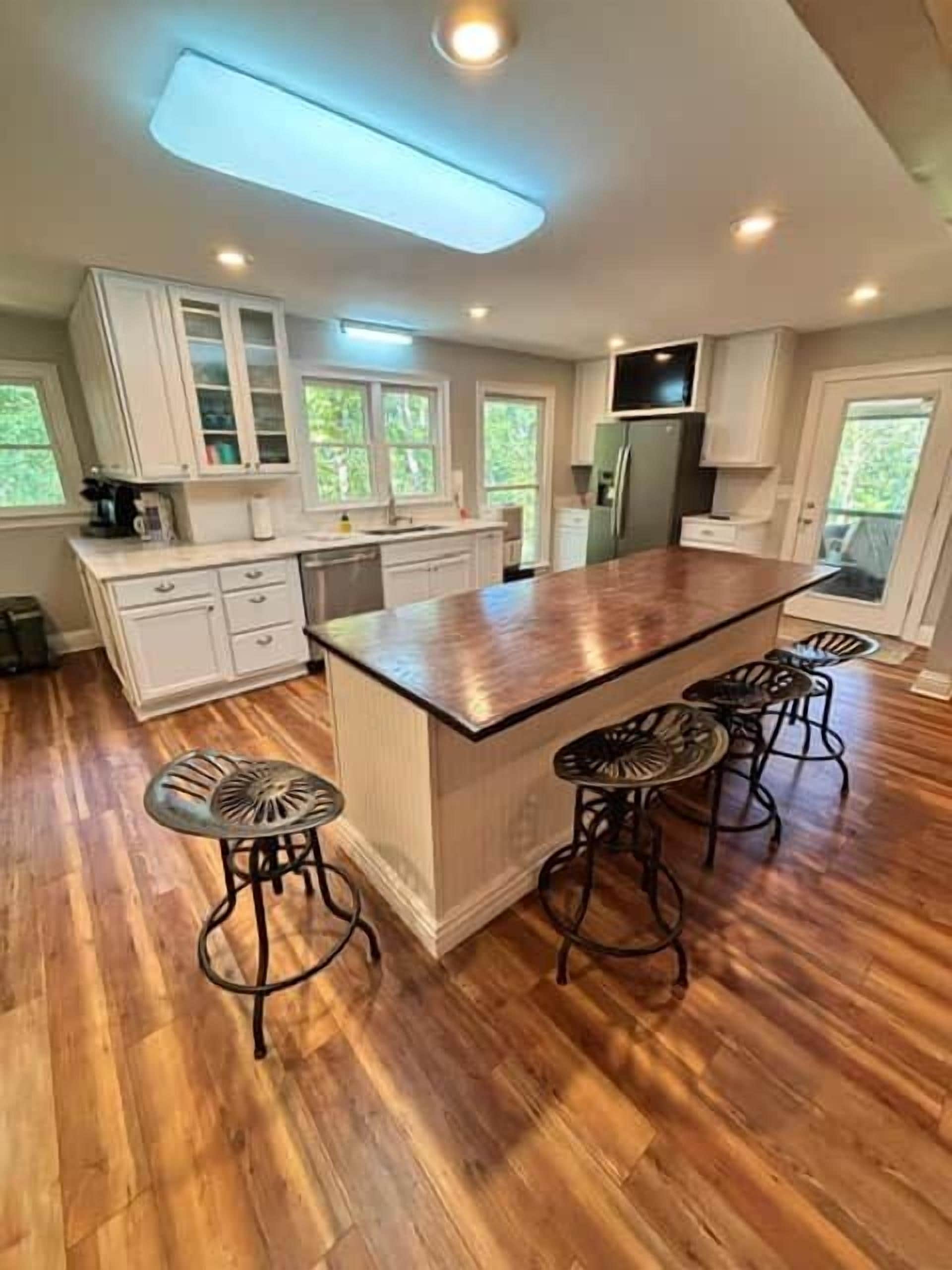 A kitchen with a large island, bar stools, and white cabinetry.