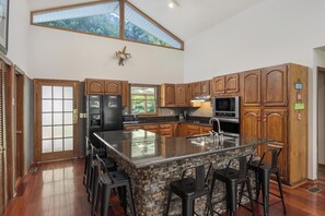 A spacious kitchen with a large island, wooden cabinets, and a stone backsplash. - Perfect Getaway on the Water~Beautiful Gorge Views~11 miles to Downtown! (Chattanooga)