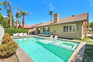 Propiedad residencial con piscina, sillas de descanso y zona de patio.