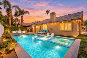 Ein Wohnhaus mit Swimmingpool, Außenbereich mit Sitzgelegenheiten und einer gut beleuchteten Terrasse.