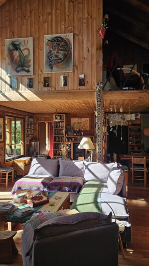 A cozy cabin interior with a large bed, bookshelves, and artwork on the walls. - Casa Verde Hostal Ecologico (Curacautin)