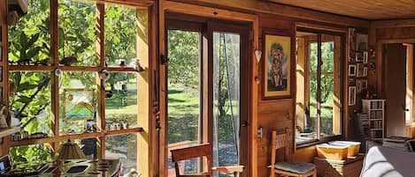 A wooden cabin interior with large windows, a dining area, and a cozy seating space.