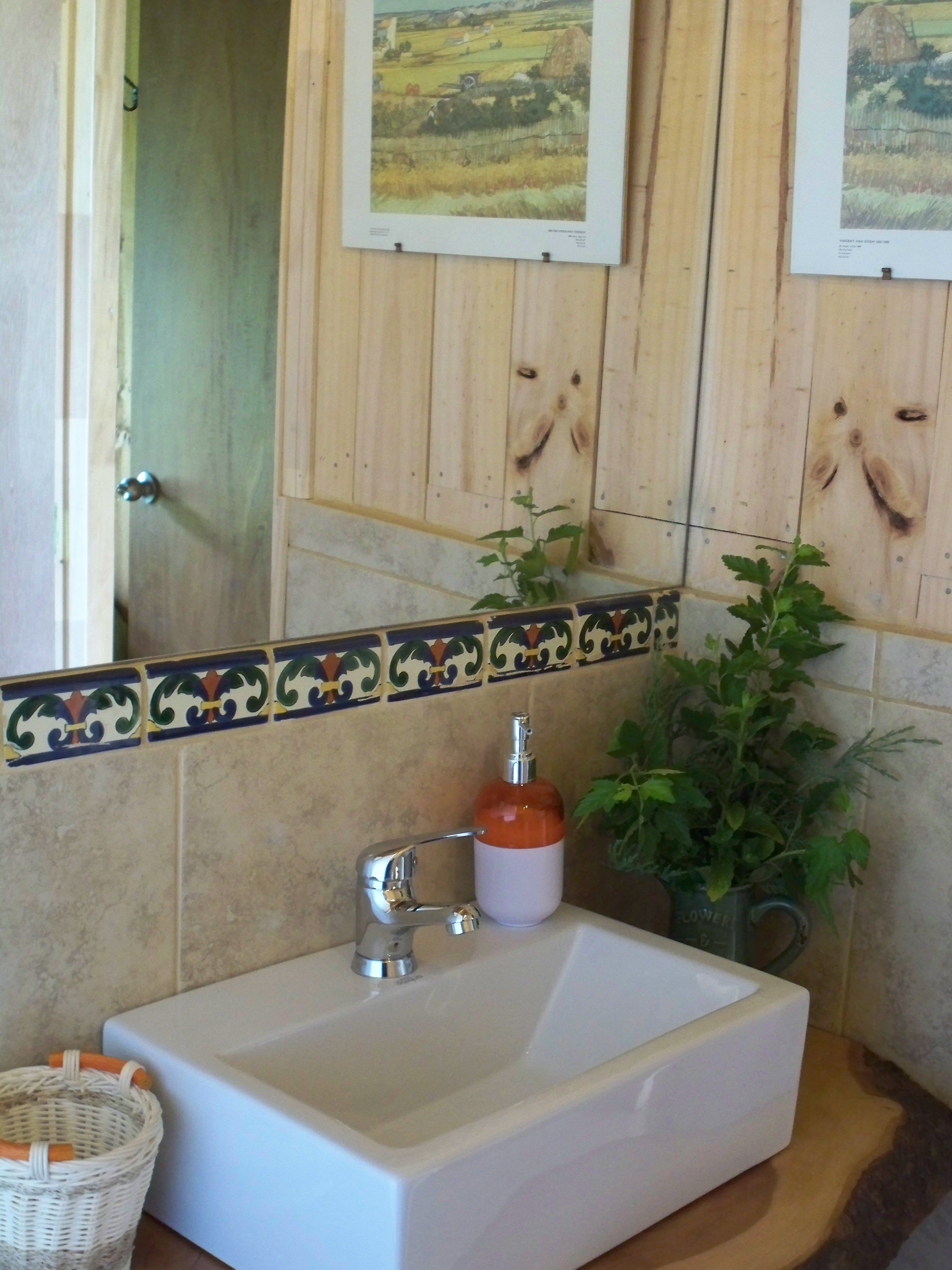A bathroom with a white sink, a mirror, and wooden paneling on the wall.