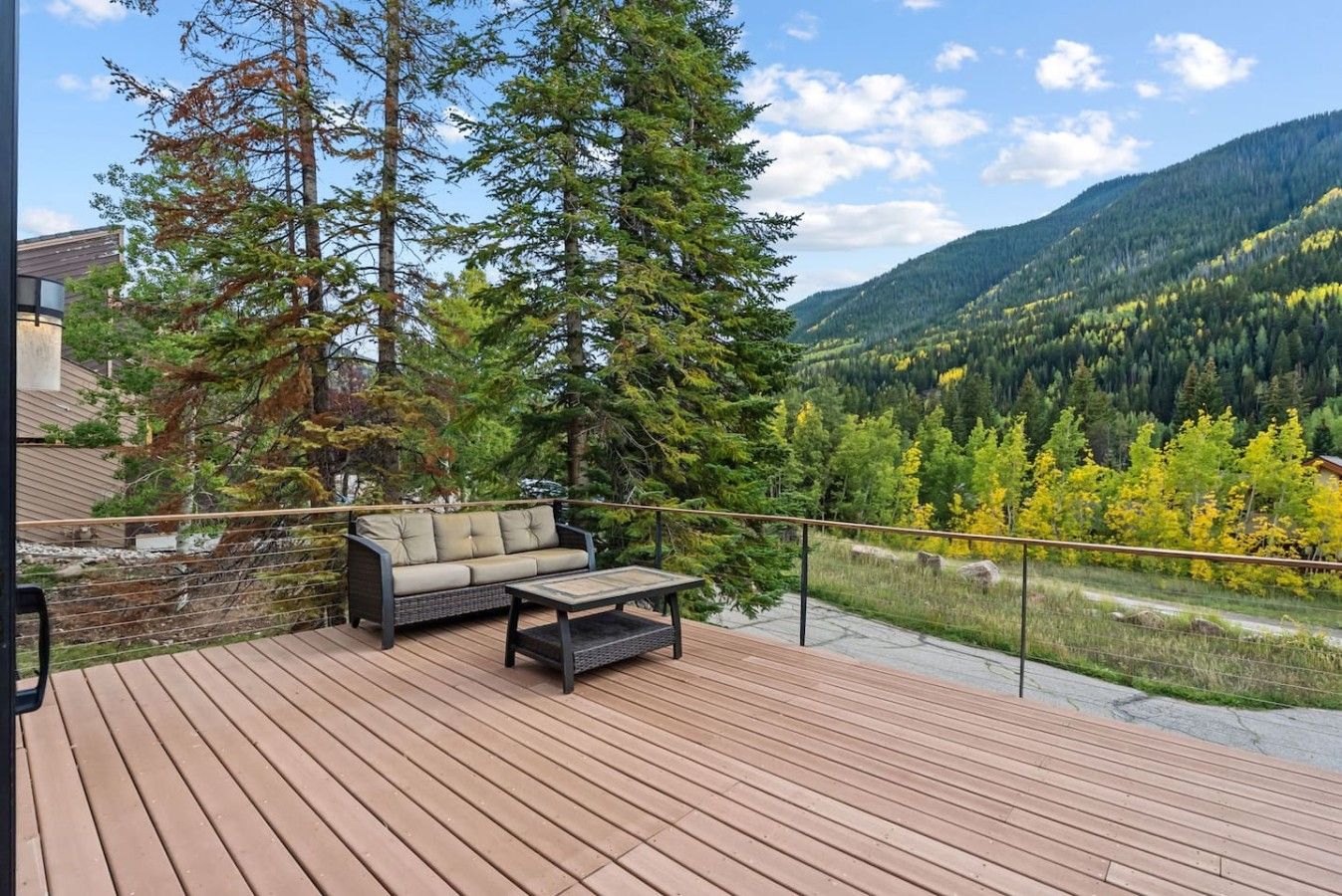 Eine Terrasse mit Sofa und Couchtisch, mit Blick auf eine gebirgige Landschaft.