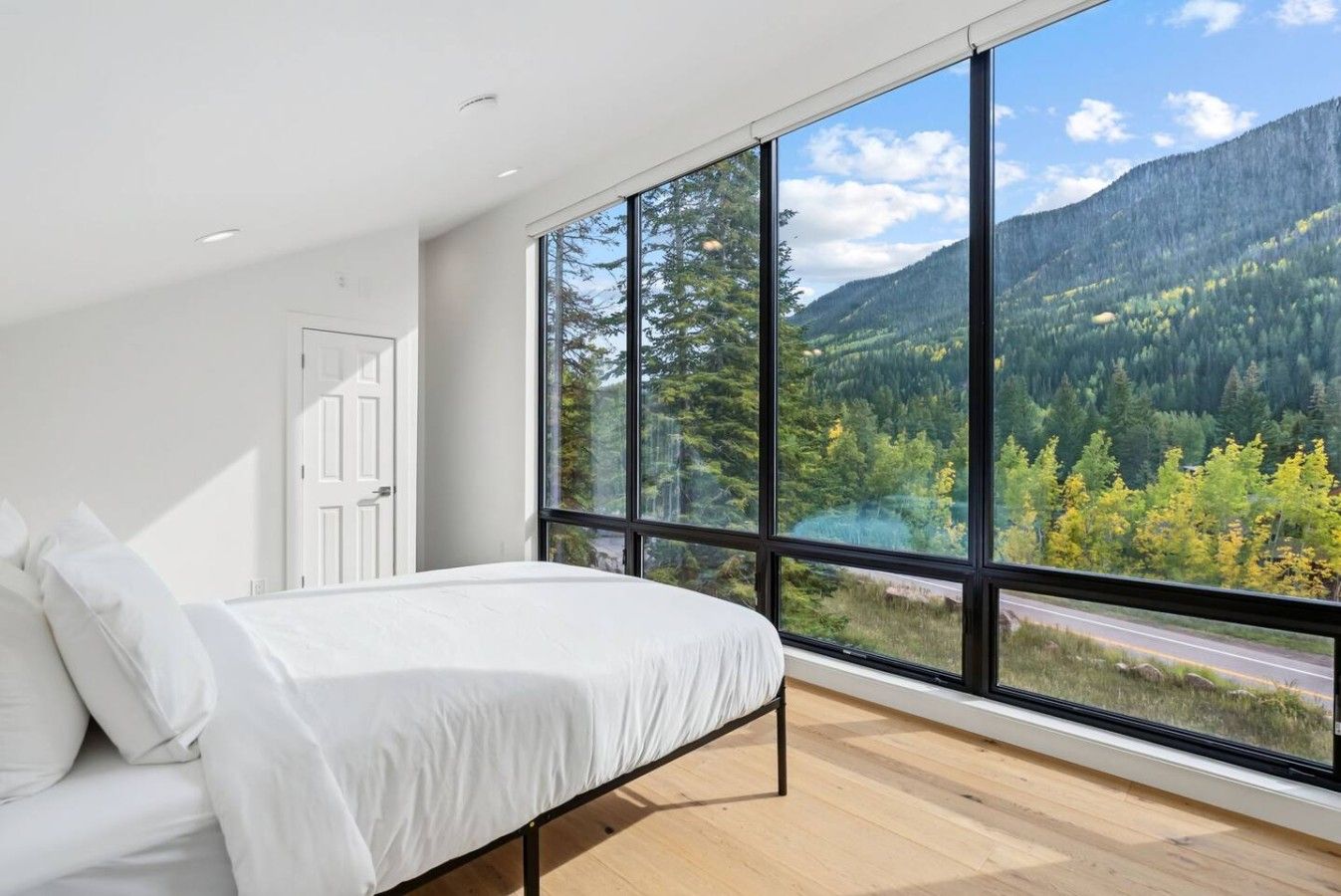 A bedroom with a large window, a bed, and a door.