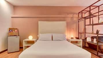 Ein Hotelzimmer mit Bett, Nachttischen, einem kleinen Kühlschrank und einem Regal.