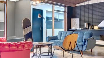 Ein modernes Wohnzimmer mit einem blauen Sofa, einem roten Sessel und einem runden Couchtisch.