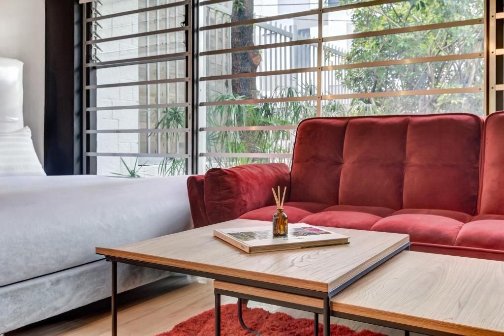 Un soggiorno moderno con un divano rosso, un tavolino in legno e vista attraverso una finestra con inferriate.