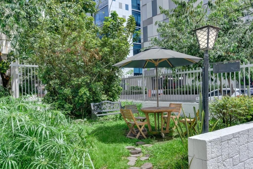 Un espace extérieur aménagé avec une table et des chaises, entouré de verdure et délimité par une clôture blanche.