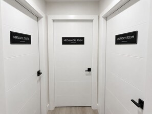 Ein Flur mit drei Türen, die mit 'PRIVATE SUITE', 'MECHANICAL ROOM' und 'LAUNDRY ROOM' beschriftet sind.