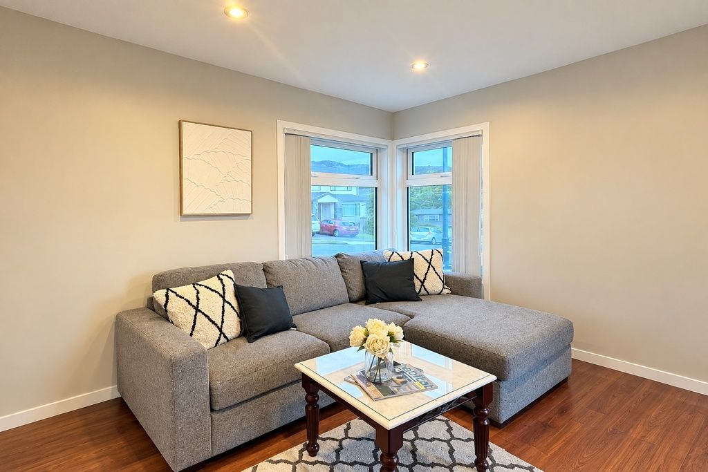 A living room with a grey sectional sofa, a coffee table with magazines, and a framed picture on the wall.