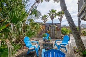 A wooden deck with blue chairs, a small table, and a decorative fence with sunflowers and a wooden door. - BC2--Sleeps 4 Adults/2 Kids, 1 BR/1 Bath, Walk to Beach, Pool, Hot Tub, Dogs OK! (Port Aransas)