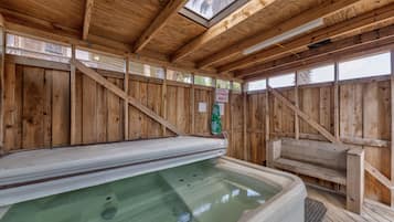 A wooden spa area with a hot tub, wooden walls, and a skylight.