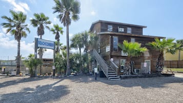 A wooden building with a sign reading 'BEACHCOMBER' and a staircase leading to the entrance.