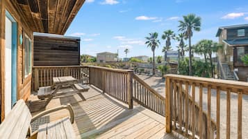 A wooden deck with a view of the beach and palm trees.