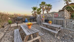 A patio with wooden benches, a grill, and a string of lights. - BC2--Sleeps 4 Adults/2 Kids, 1 BR/1 Bath, Walk to Beach, Pool, Hot Tub, Dogs OK! (Port Aransas)