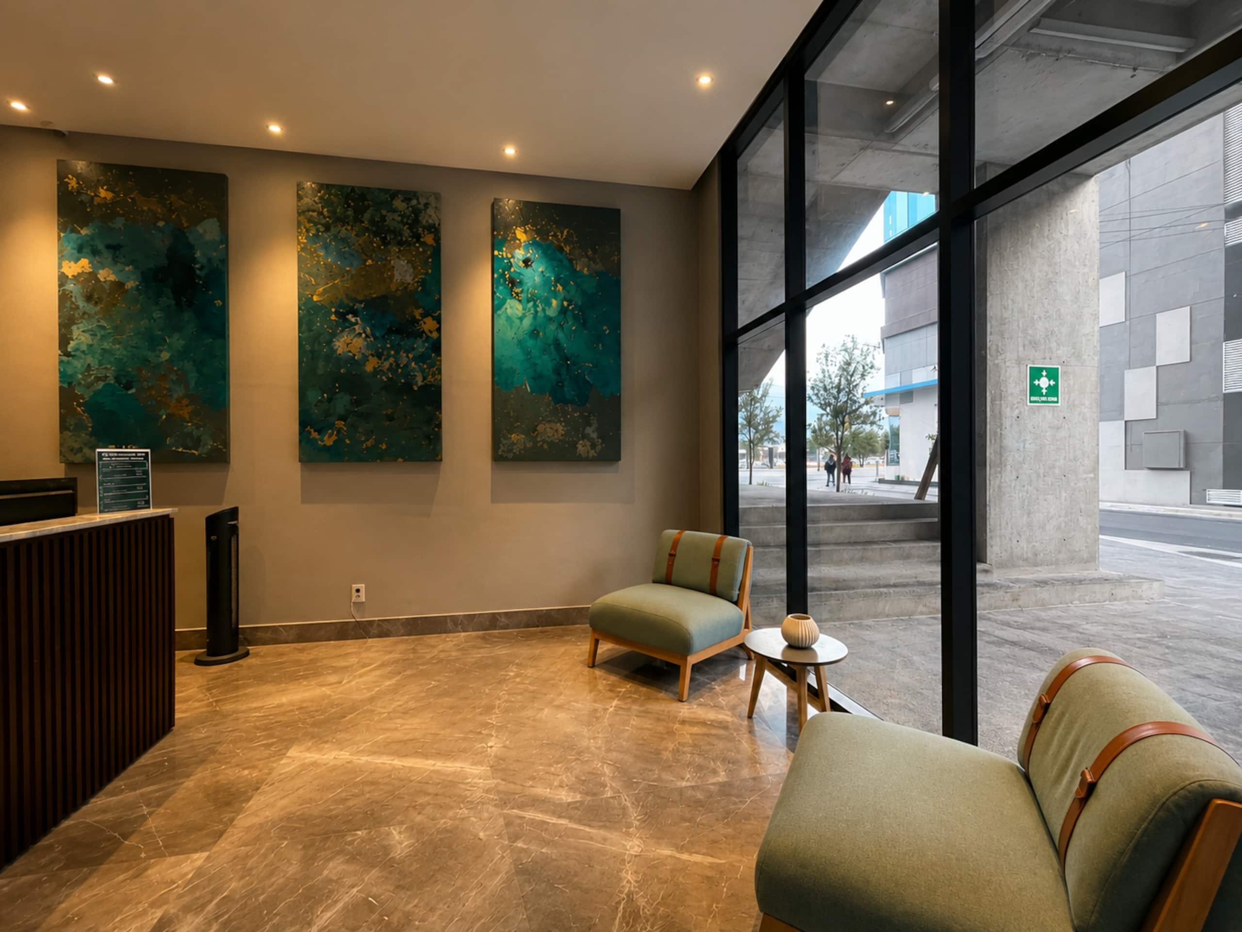 A reception area with a reception desk, seating, abstract wall art, and large windows.