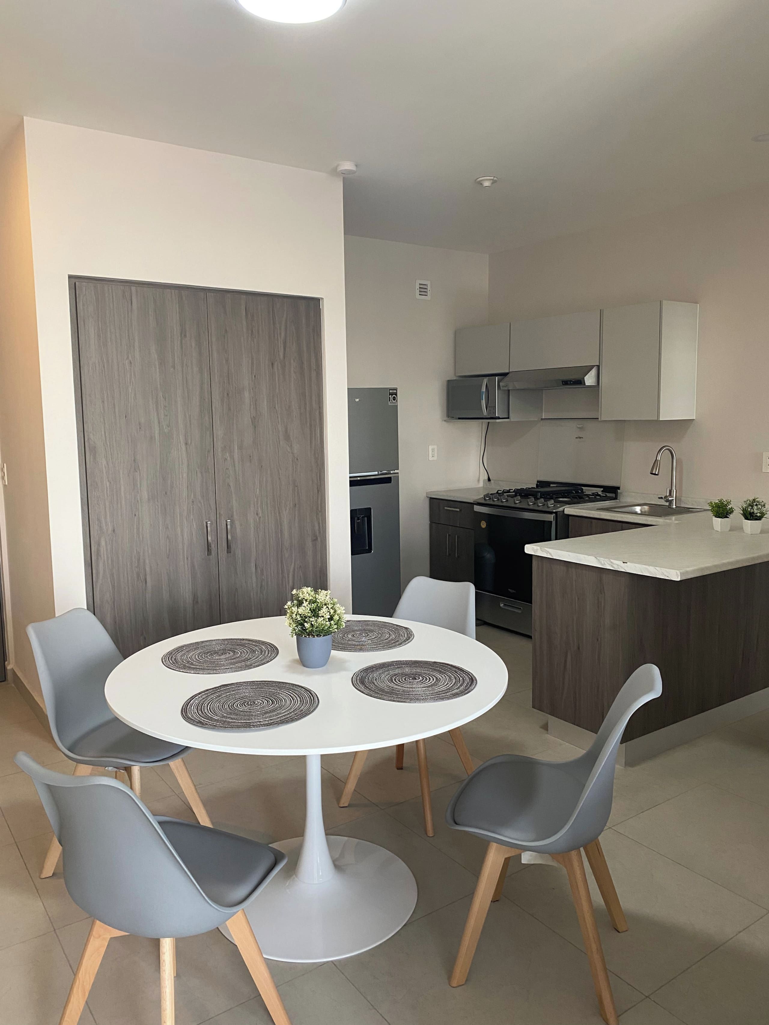 Una cocina moderna con una isla central, un comedor con cuatro sillas y un amplio armario de madera.