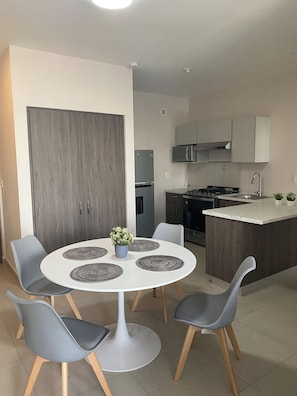 Una cocina moderna con una isla central, un comedor con cuatro sillas y un amplio armario de madera.