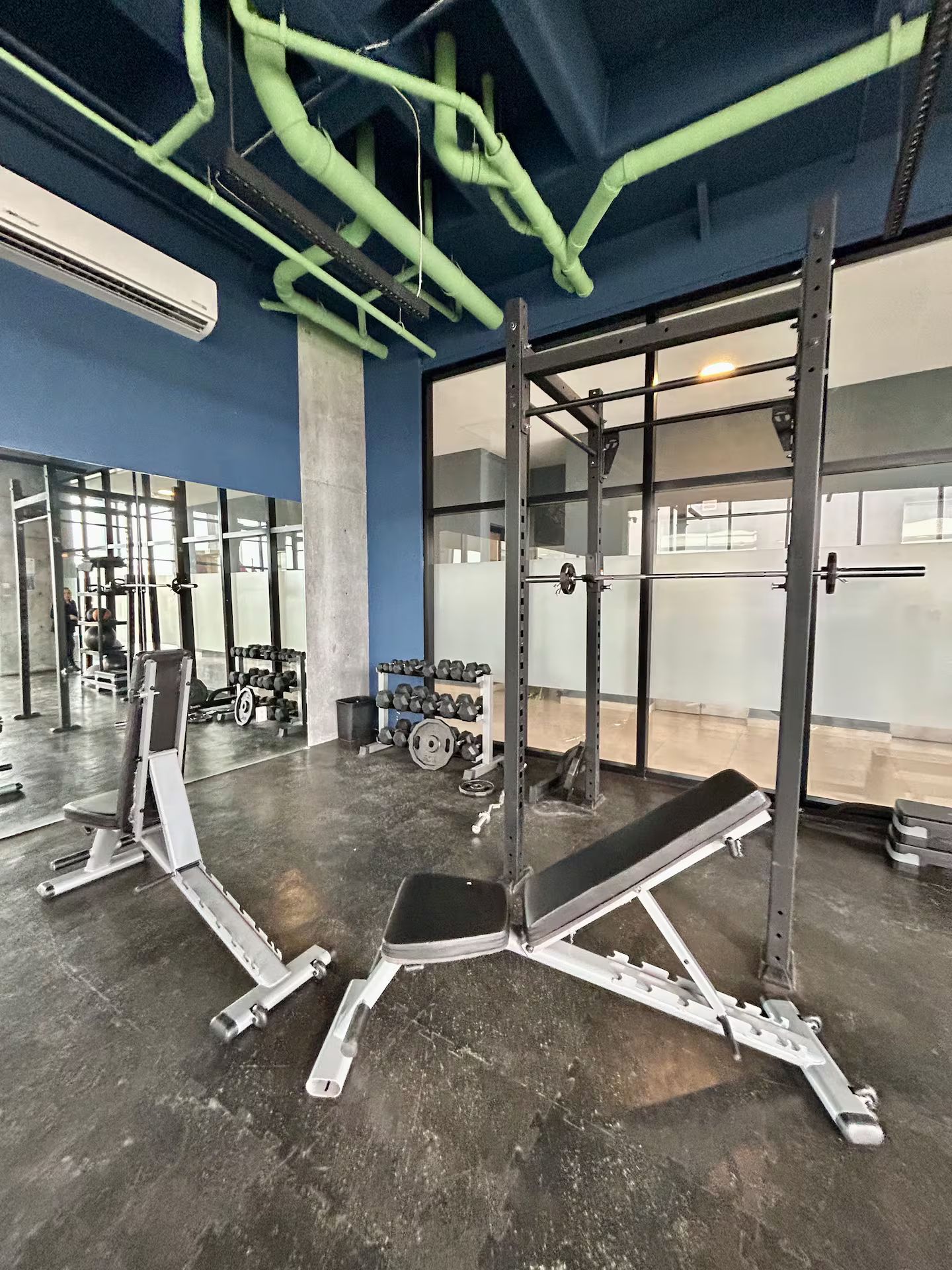 A gym with weightlifting equipment, including barbells and dumbbells, and a bench press.