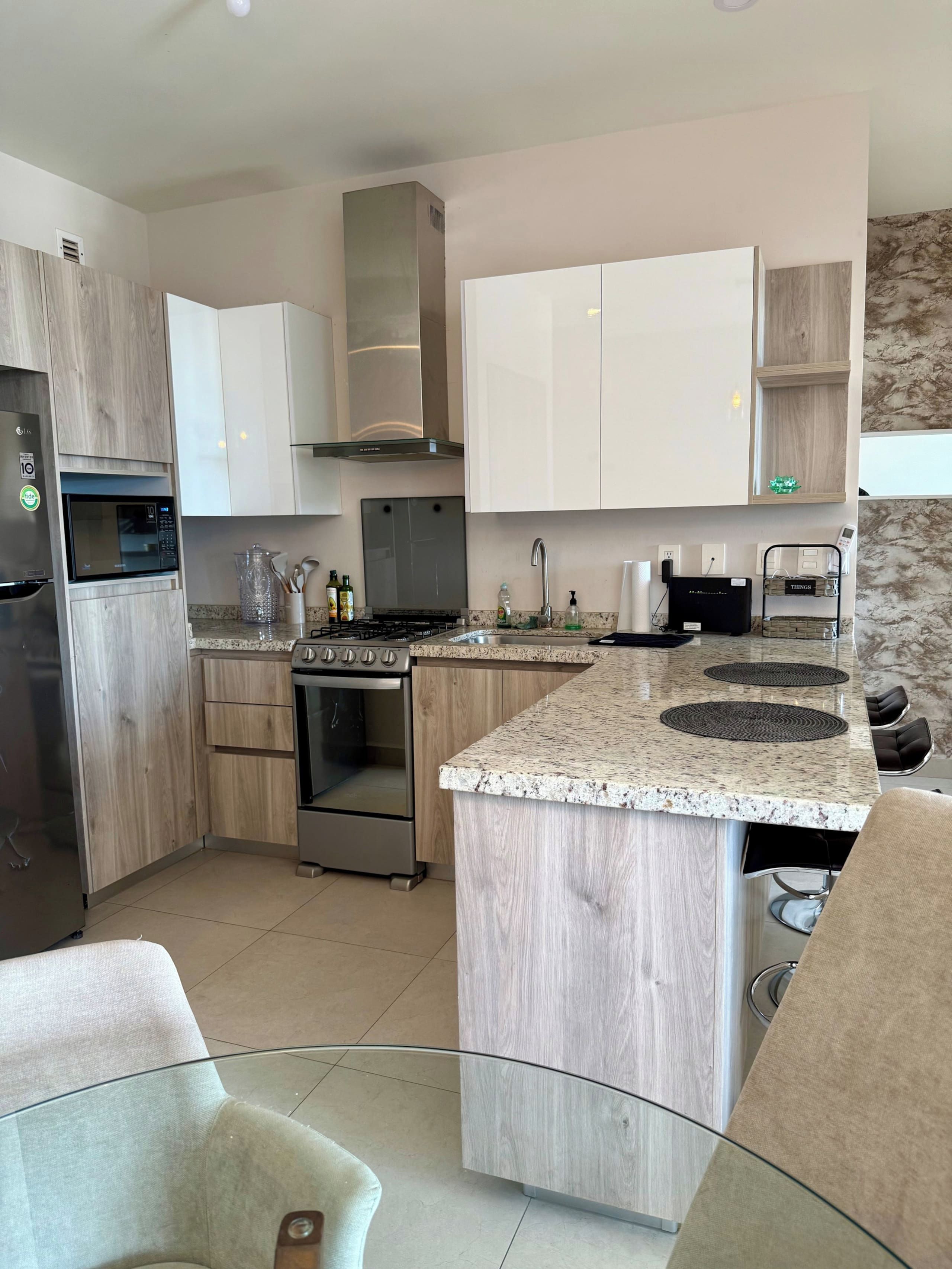 A modern kitchen with a central island, stainless steel appliances, and a marble countertop.