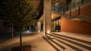 An outdoor area with steps leading to a building entrance, a tree, and a parked car.