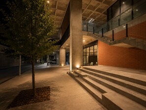 An outdoor area with steps leading to a building entrance, a tree, and a parked car. - Arena Vive El Parque Apartamentos  (Monterrey)
