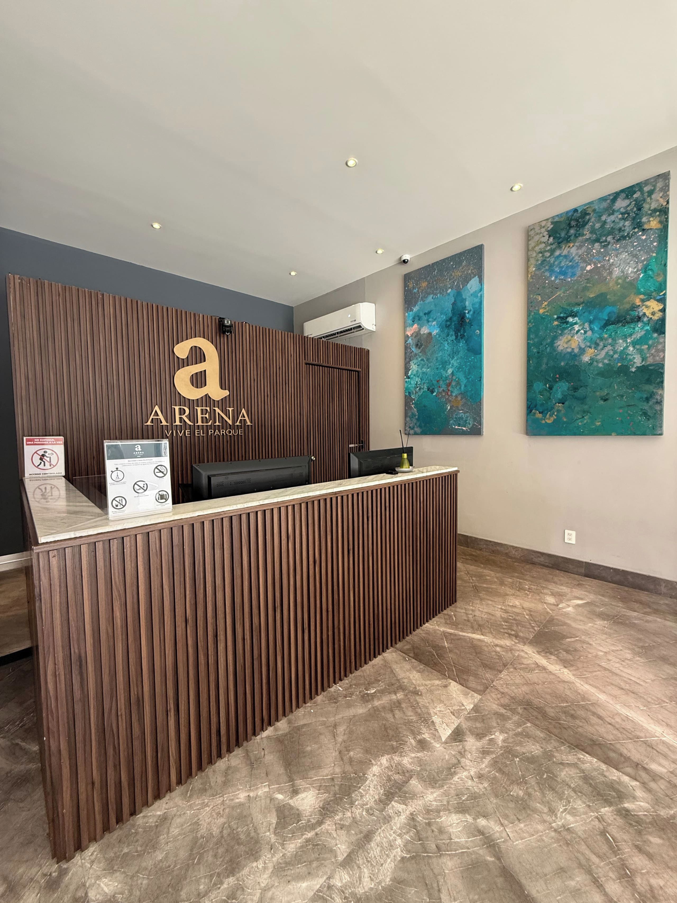 A reception desk with a wooden finish, a logo, and a sign with icons. There are two abstract paintings on the wall.