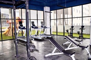 A gym with treadmills, weight benches, and exercise equipment. - Arena Vive El Parque Apartamentos  (Monterrey)