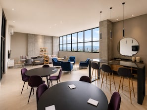 A modern conference room with a large table, multiple chairs, a bar area, and a large window offering a city view. - Arena Vive El Parque Apartamentos  (Monterrey)
