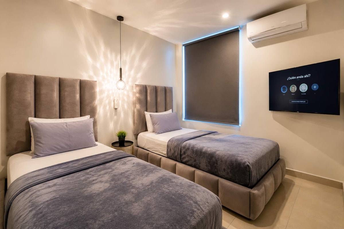 A modern bedroom with two beds, a TV, and a window.