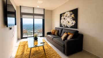 A modern living room with a sofa, a coffee table, and a large window offering a city view.