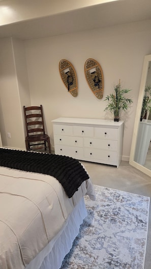 Ein Schlafzimmer mit einem Bett, einem Schminktisch, einem Stuhl und einem Spiegel.