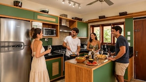 Eine moderne Küche mit einem Edelstahl-Kühlschrank, einer Mikrowelle und einer zentralen Kochinsel mit verschiedenen Lebensmitteln.
