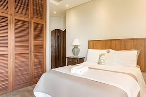 Ein Hotelzimmer mit einem Bett, einem Nachttisch, einer Lampe und einem Holzschrank.
