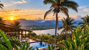Ein Resort mit Pool, Palmen und Blick auf Berge und Wasser.
