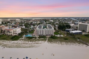 Een hotel aan de kust met een centraal binnenhof, omringd door toegang tot het strand en uitzicht op de oceaan.