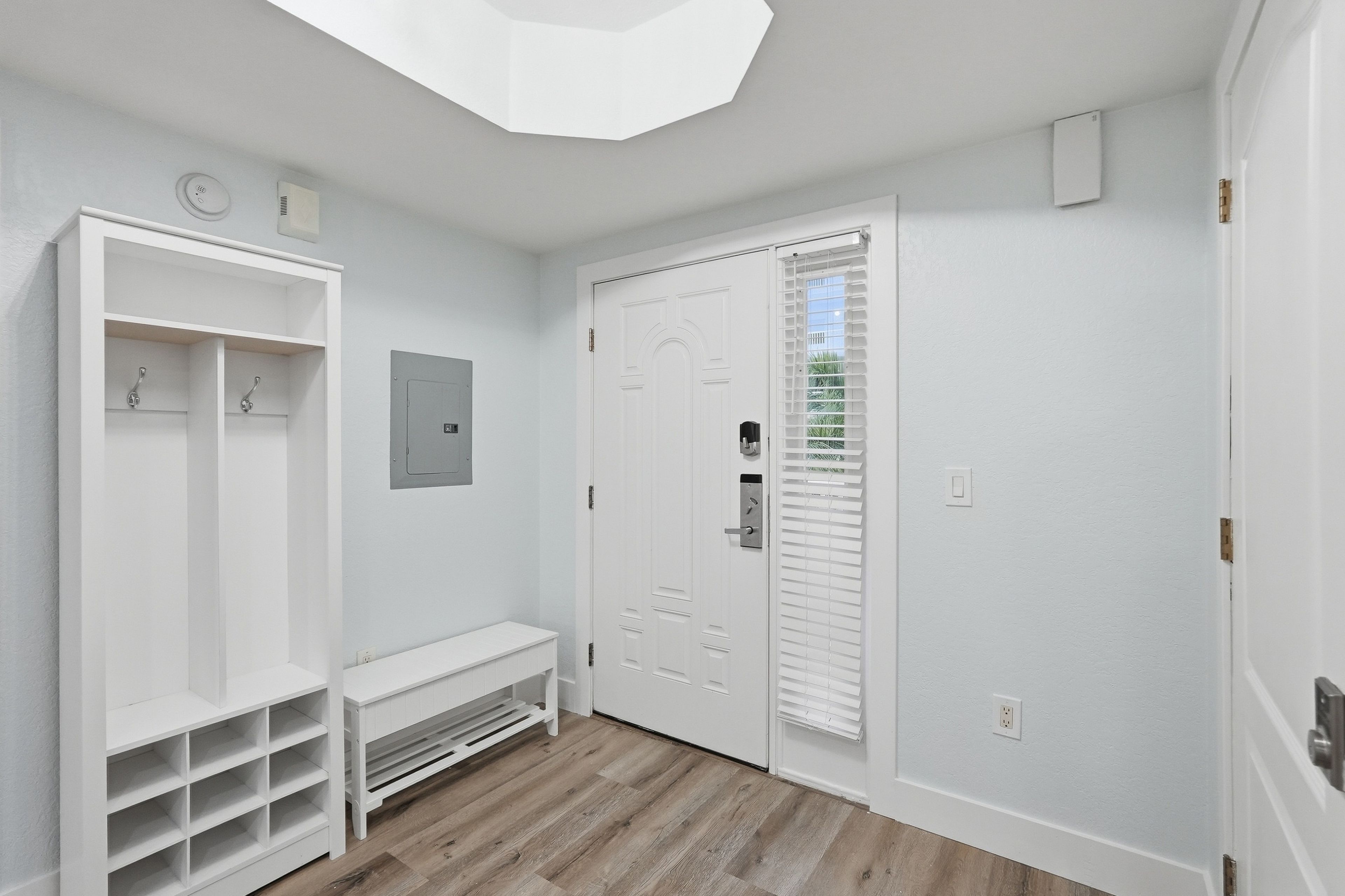 A hallway with a white door, a coat rack, and a bench.
