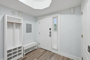 A hallway with a white door, a coat rack, and a bench. - Elevated Beach Escape on Treasure Island (Treasure Island)