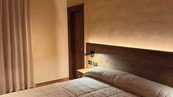 A bedroom with a wooden ceiling, a bed with a headboard, a nightstand, and a wall-mounted lamp.