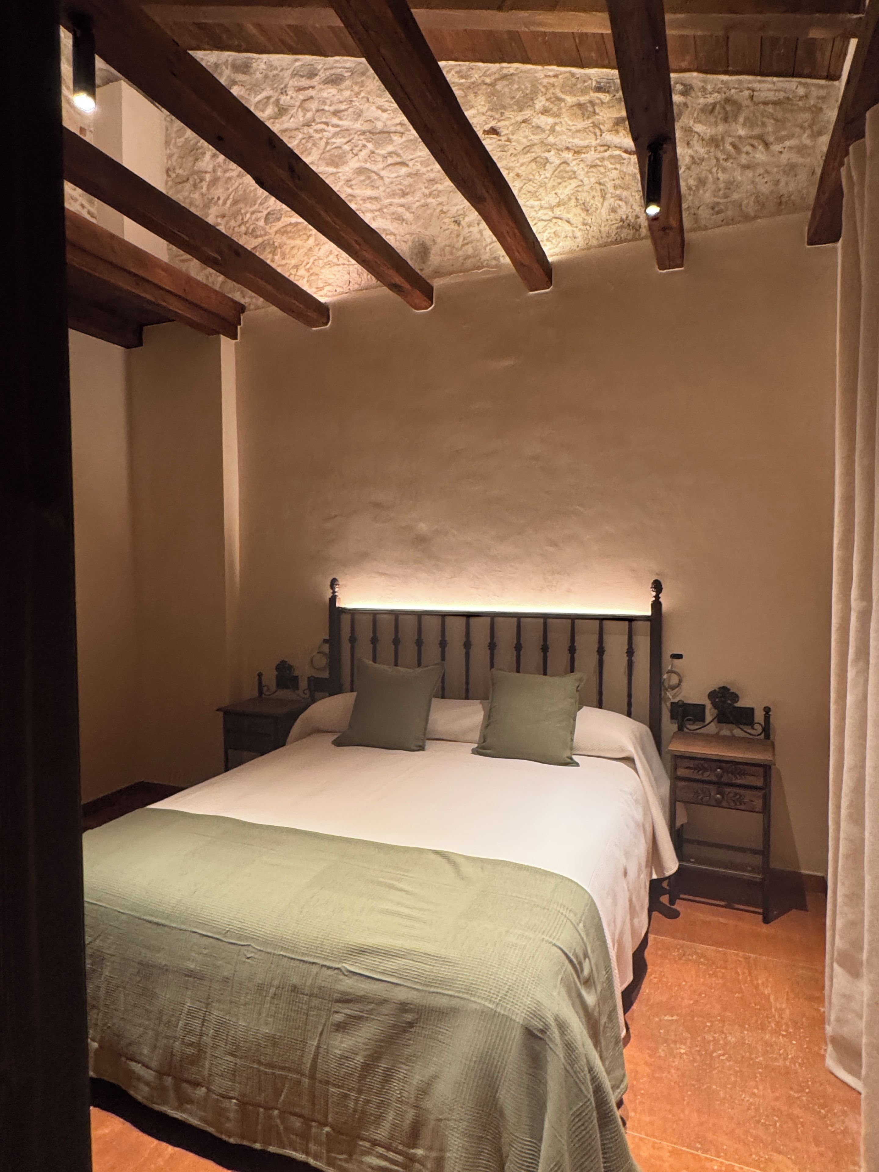 Un dormitori amb un llit, fallegueres i una paret de pedra.