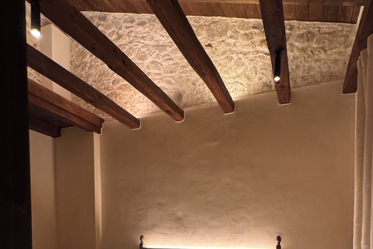 Una camera da letto con un letto, comodini e una parete in pietra.