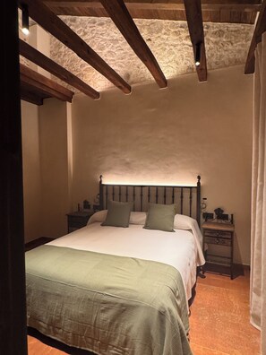 Una camera da letto con un letto, comodini e una parete in pietra.